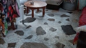 Ein Zimmer mit Steinmuster-Boden, einer Couch, einem kleinen Tisch und einem Bücherregal.