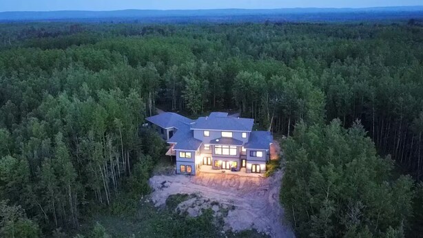 A large, multi-story house surrounded by dense forest. - Cedar Studio w Full Kitchen + Living @ Whitetail Estates (Babbitt)