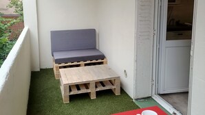 Ein Balkon mit einer Holzbank, einem kleinen Tisch und zwei weißen Tassen.