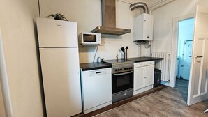 Eine kleine Küche mit Kühlschrank, Mikrowelle, Herd und Schränken.