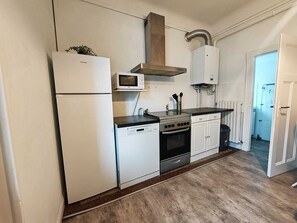 Eine kleine Küche mit Kühlschrank, Mikrowelle, Herd und Schränken.