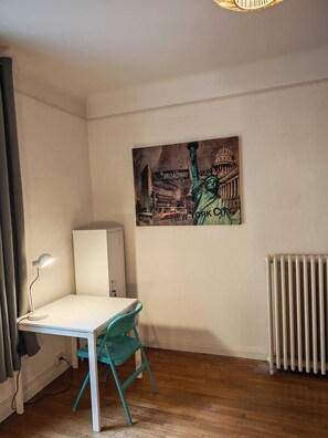 A room with a desk, chair, radiator, and a painting of the Statue of Liberty. - Vacation Rental in Metz - Apartment for up to 4 people (Metz)