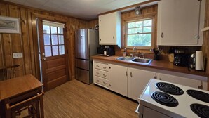 Una cucina compatta con pareti in legno, un frigorifero, un fornello e una finestra.