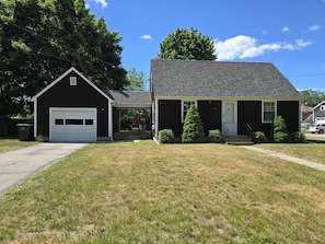 A two-story house with a garage, a front porch, and a well-maintained lawn.