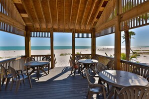 Eine Holzterrasse mit Tischen und Stühlen mit Blick auf einen Strand.