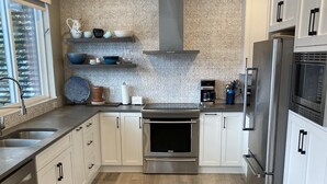 Een moderne keuken met een centraal eiland, roestvrijstalen apparatuur en een decoratieve spatwand.