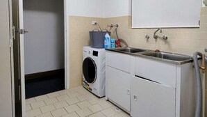 Pesuhuone, jossa on pesukone, pesuallas ja pyyheteline.