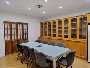 Ein Essbereich mit einem weißen Tisch, grauen Stühlen, Holzschränken mit Glastüren und einem weißen Kühlschrank.