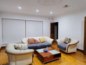 Un salon comprenant un canapé, deux fauteuils, une table basse et une grande fenêtre.