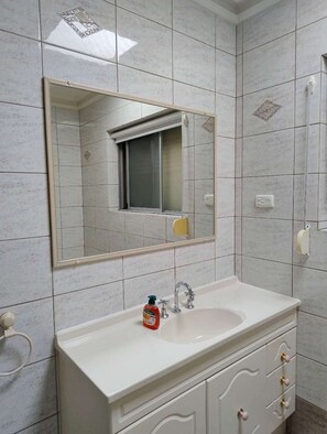 Ein Badezimmer mit einem wei ßen Waschbecken, einem Spiegel und einer gefliesten Wand.