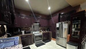 Una cocina con armarios de madera oscura, un refrigerador de acero inoxidable, una estufa a gas y un microondas.