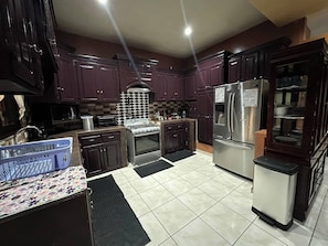 A kitchen with dark wooden cabinets, a stainless steel refrigerator, a gas stove, and a microwave.