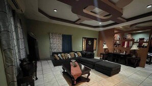 Una sala de estar con sofá, reposapiés, mesa de centro y mueble para televisor.