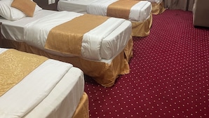 A hotel room with three single beds, a red carpet, and a ceiling light. - Rimas Al Anoud Hotel (Makkah)