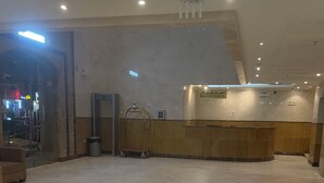 A hotel reception area with a reception desk, a gold-framed cart, and a marble floor. - Rimas Al Anoud Hotel (Makkah)