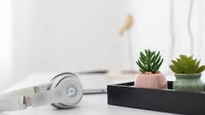 A pair of headphones, a small pink pot with a succulent, and a green pot with a succulent on a white surface. - Locanda Antica Bribano (Sedico)