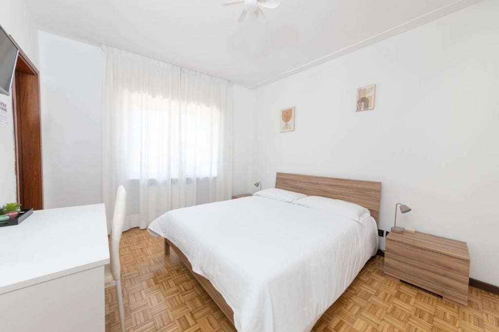 A bedroom with a bed, bedside table, and a desk.