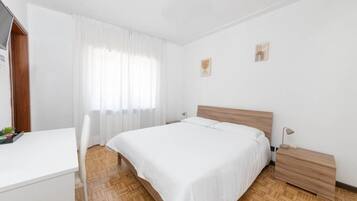 A bedroom with a bed, bedside table, and a desk.