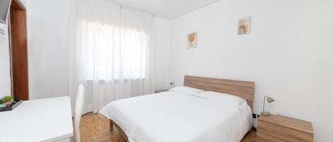 Un dormitorio con cama, mesita de noche y escritorio.
