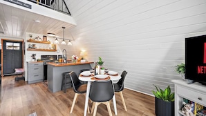 A modern kitchen with a dining area, a TV, and a bookshelf.