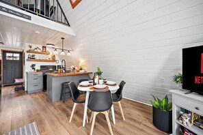 A modern kitchen with a dining area, a TV, and a bookshelf.