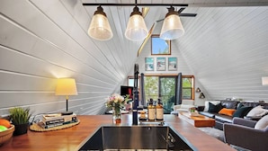 A modern kitchen with a central island, a dining area with a table and chairs, and a cozy living room with a sofa and a fireplace.