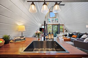 A modern kitchen with a central island, a dining area with a table and chairs, and a cozy living room with a sofa and a fireplace.