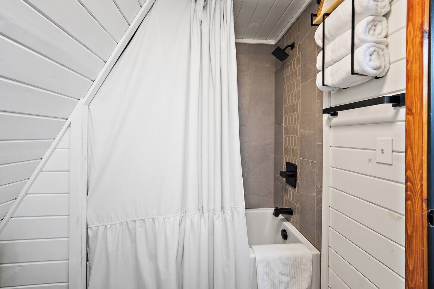 A bathroom with a shower curtain, a bathtub, and towels on a rack.
