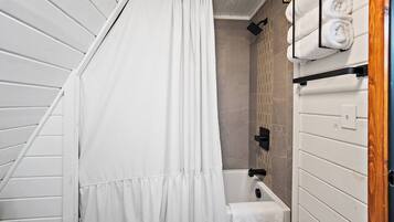 A bathroom with a shower curtain, a bathtub, and towels on a rack.
