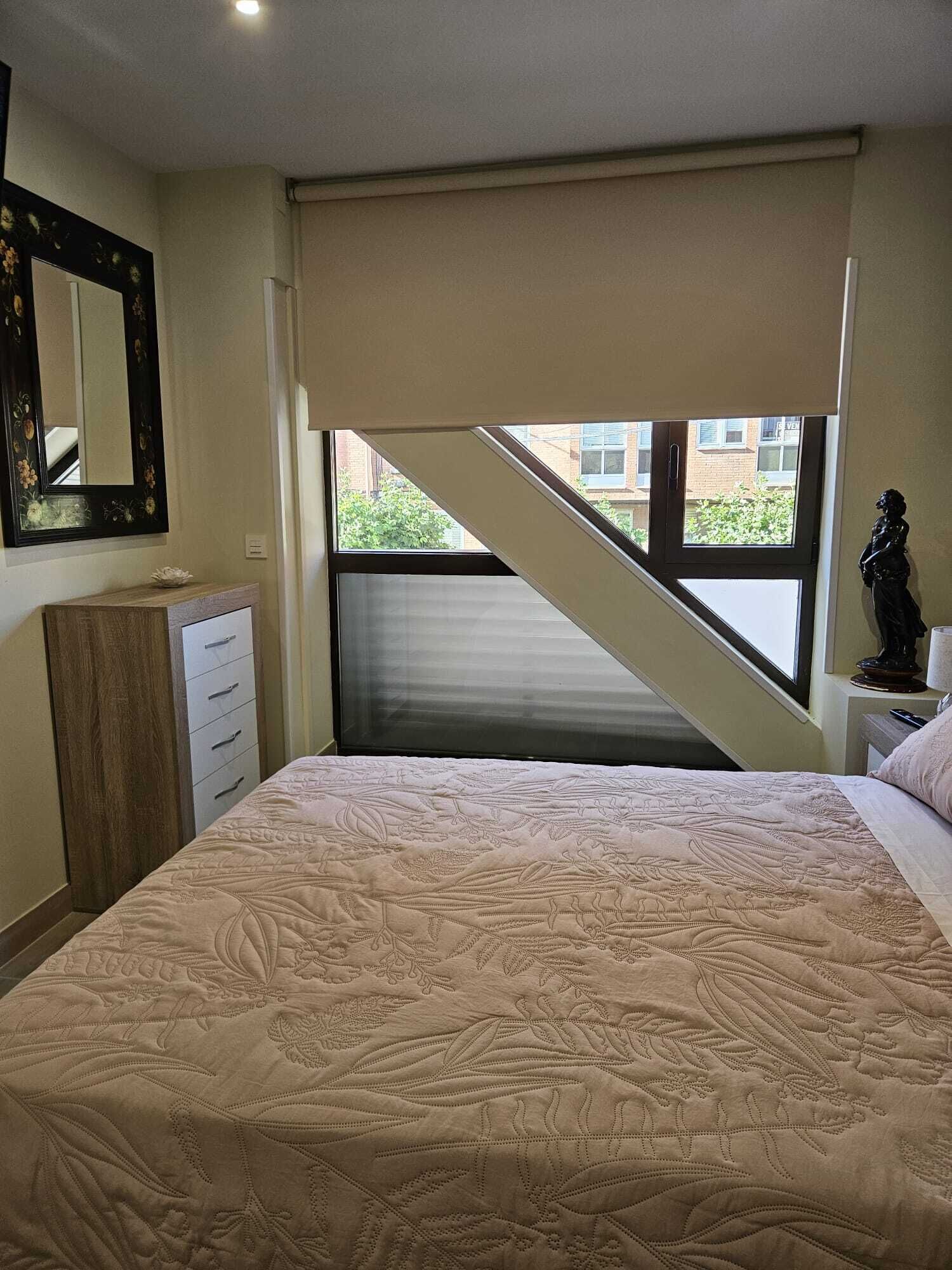 Une chambre à coucher comprenant un lit, une commode, un miroir, une fenêtre et une statue.