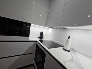 A modern kitchen with a built-in microwave, a coffee machine, and a paper towel holder.
