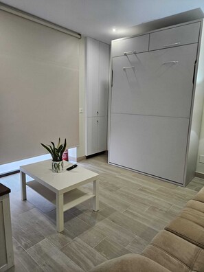 A modern room with a white wardrobe, a small table with a plant, and a beige sofa.