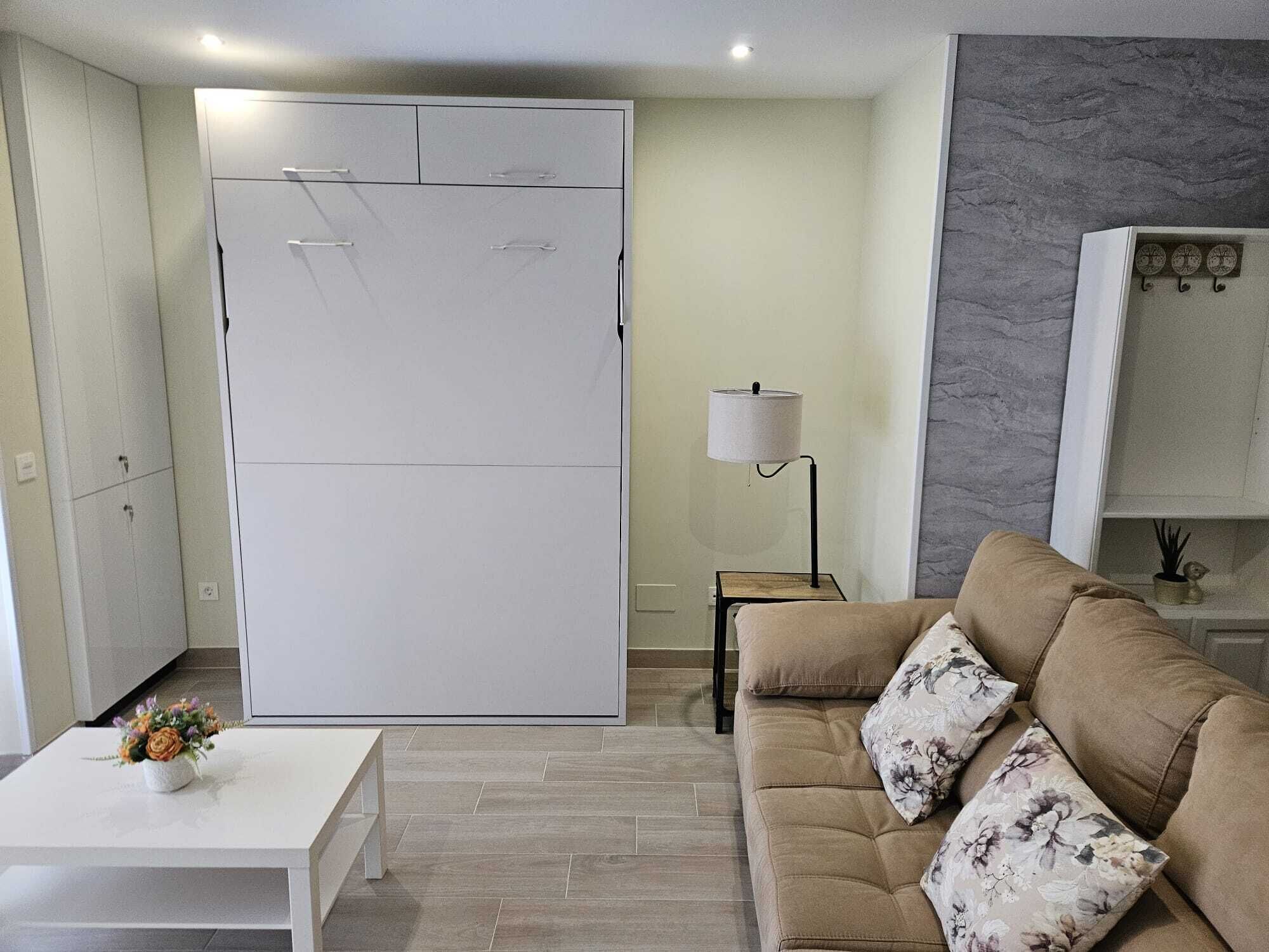 A modern living room with a sofa, a coffee table, a lamp, and a wardrobe.