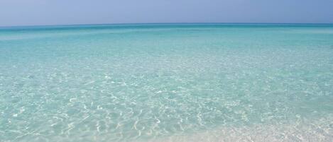 A beach with clear turquoise water and white sand.