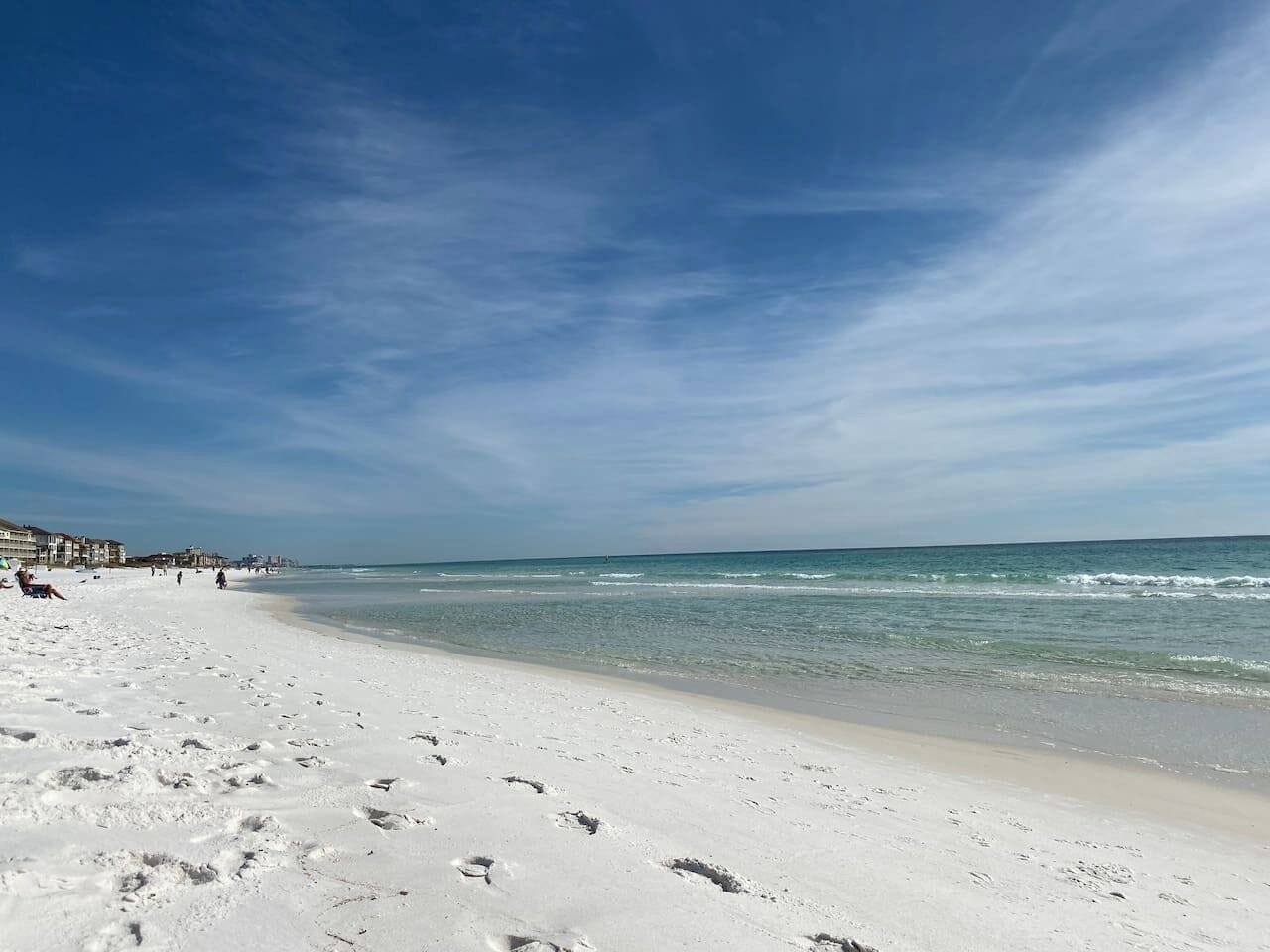 A beach with white sand, clear blue sky, and calm sea.