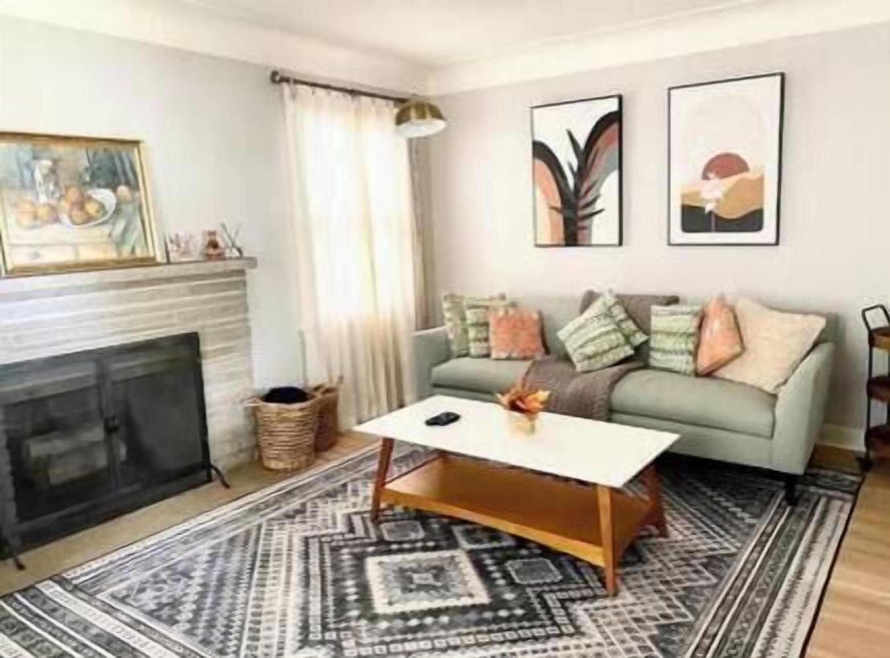 Una sala de estar con chimenea, sofá, mesa de centro y una obra de arte en la pared.