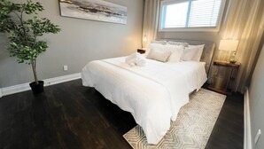 A bedroom with a large bed, a potted plant, a window with curtains, and a painting on the wall. - Chic Stay in Wortley – Walk to Downtown & Parks (London)