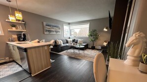 A modern kitchen with a central island, dark wooden flooring, and a dining area with a white table and chairs. - Chic Stay in Wortley – Walk to Downtown & Parks (London)