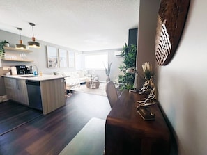Eine moderne Küche mit Geschirrspüler, ein Essbereich mit Holztisch und -stühlen sowie ein Wohnzimmer mit Sofa und Couchtisch.