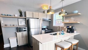 A modern kitchen with a central island, stainless steel appliances, and wooden bar stools.