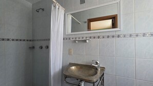 Une salle de bain avec une douche, un lavabo et un miroir.
