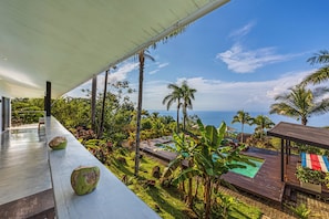 Ein moderner Außenbereich mit Pool, Palmen und Meerblick.
