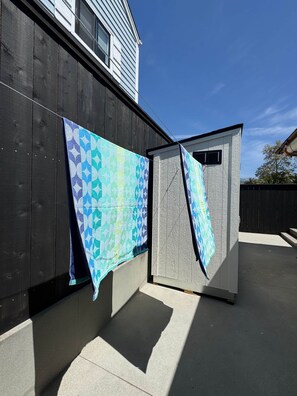 Ein kleines, eingeschossiges Gebäude mit dunkler Holzfassade und einer weißen Außenwand.