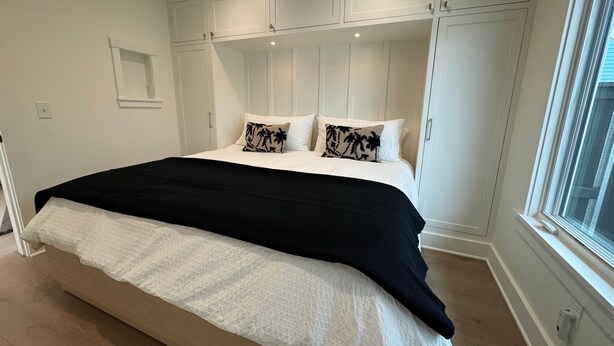 Ein Schlafzimmer mit einem Bett, weißen Wänden und eingebauten Stauraumschränken.