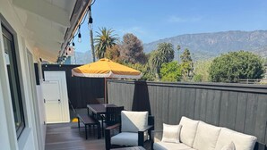 Eine möblierte Terrasse mit einer Couch, Sesseln, einem Tisch und einer hölzernen Bank.