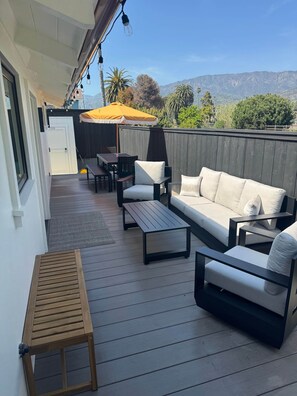 Eine m öblierte Terrasse mit einer Couch, Sesseln, einem Tisch und einer hölzernen Bank.