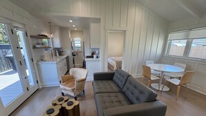 Ein modernes Interieur mit einer Couch, Sesseln, einem Esstisch und einer Küchenzeile.