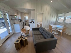 Ein modernes Interieur mit einer Couch, Sesseln, einem Esstisch und einer Küchenzeile.