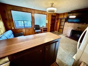 Ein Holzinterieur mit Kamin, einer Couch, einem Sessel und einer Holzauslage.