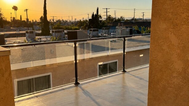 Terraza en la azotea con vista despejada al atardecer, edificios y líneas eléctricas al fondo.